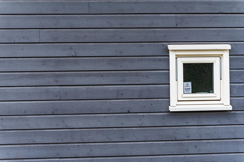 Man applying exterior sealant/caulk to the frame of an old residential window during a Florence Residential Window Replacement project.